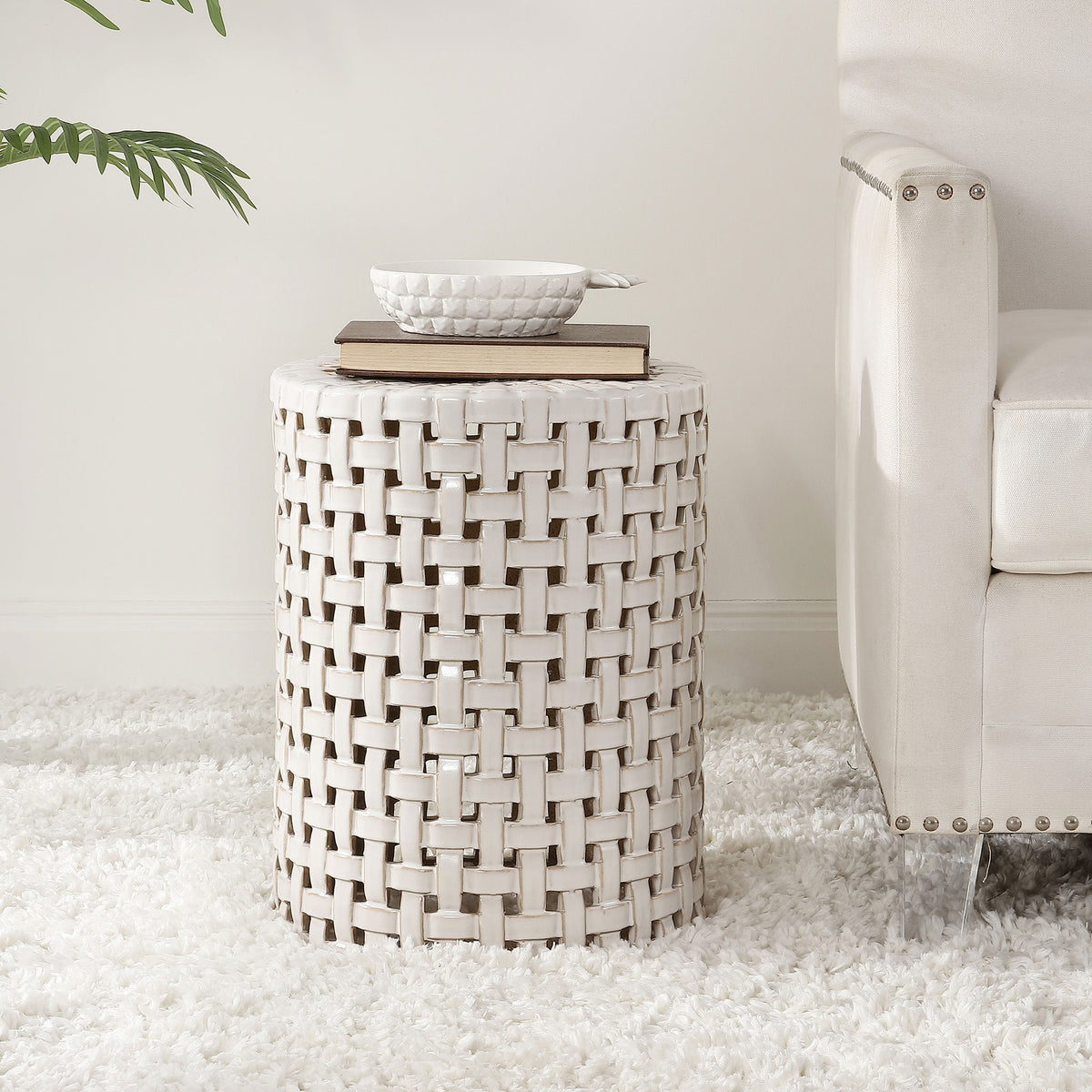 Cream ceramic stool with airy latticework holds books beside a sofa || ACS4606A || front_room