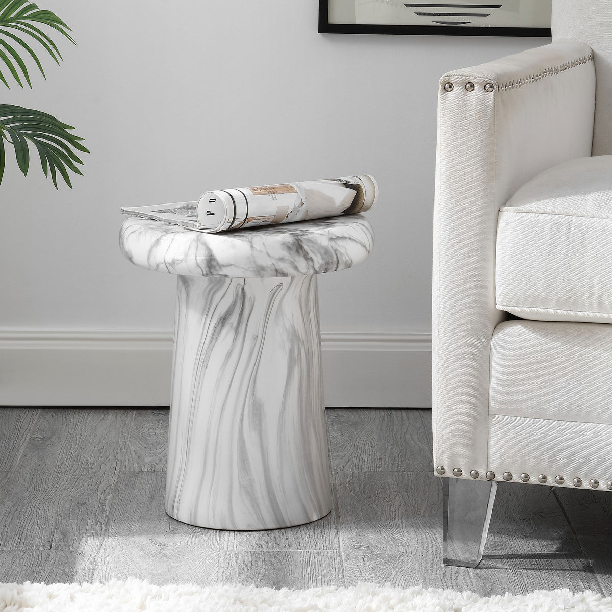 A white marble-look ceramic stool serves as a small side table beside an upholstered chair.