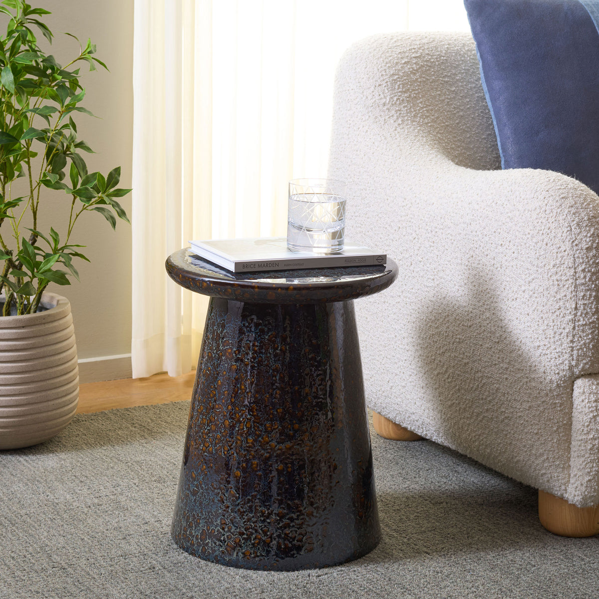 Dark blue ceramic stool serves as a compact side table beside a soft white armchair. || ACS4609B || front_angle_room