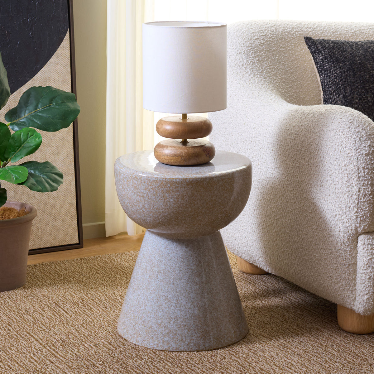 A light taupe ceramic stool doubles as a petite table for a lamp beside a plush chair. || ACS4611A || front_angle_room