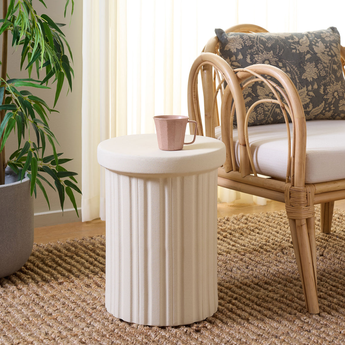 The light cream ceramic stool serves as a handy side table beside a woven lounge chair. || ACS4614A || front_angle_room