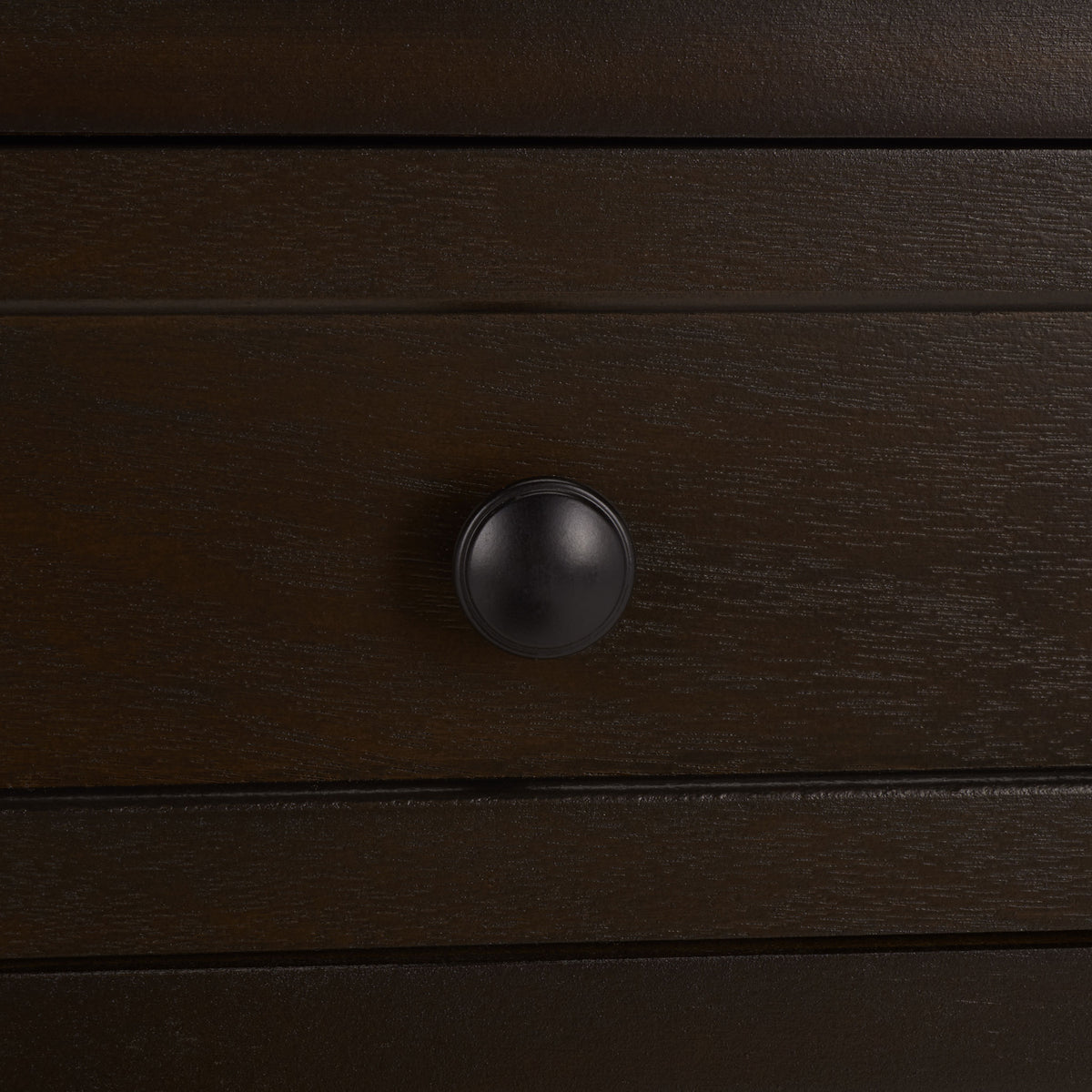An antique black knob sits at the center of a richly grained, dark brown drawer. || AMH5702H || handle_studio