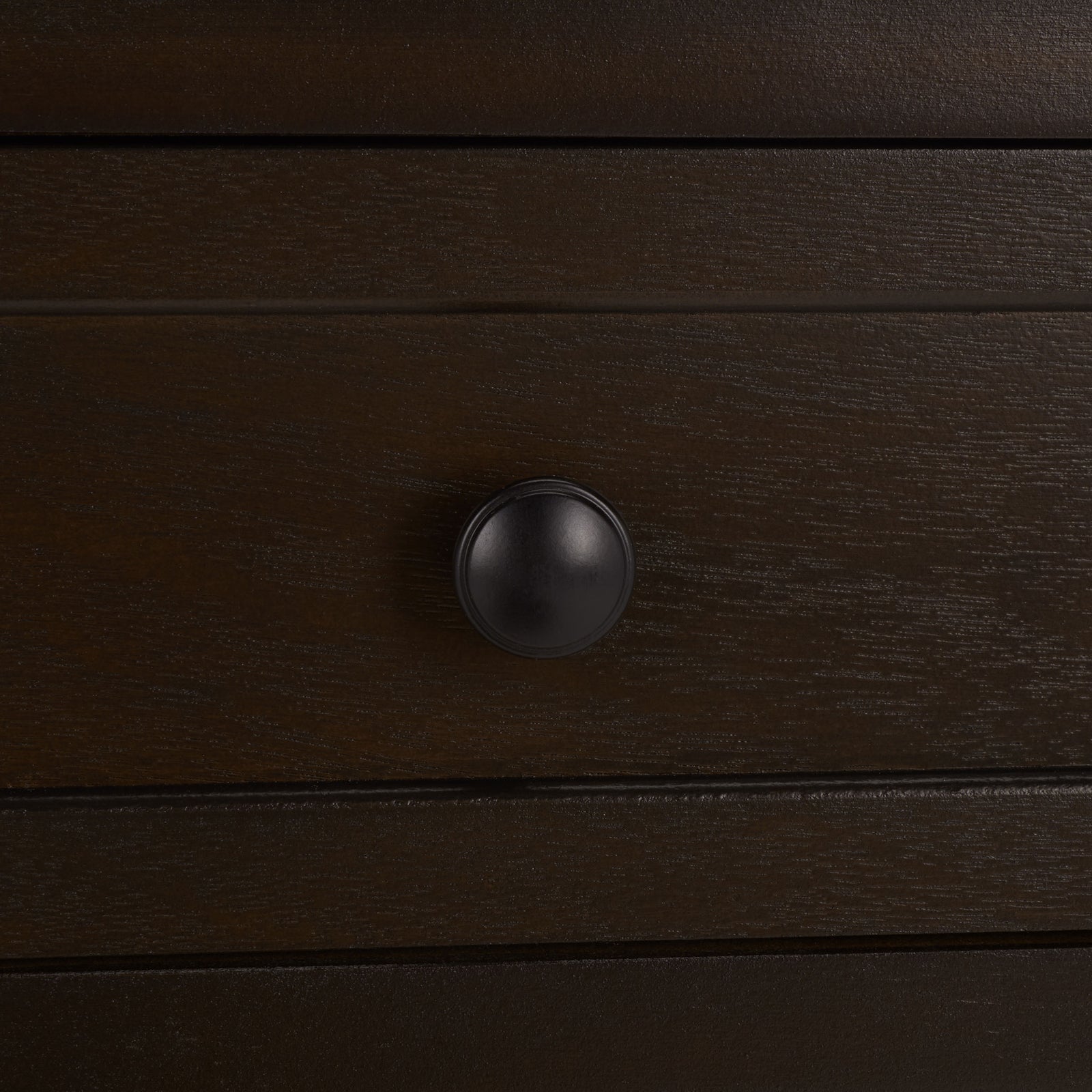 An antique black knob sits at the center of a richly grained, dark brown drawer. || AMH5702H || handle_studio