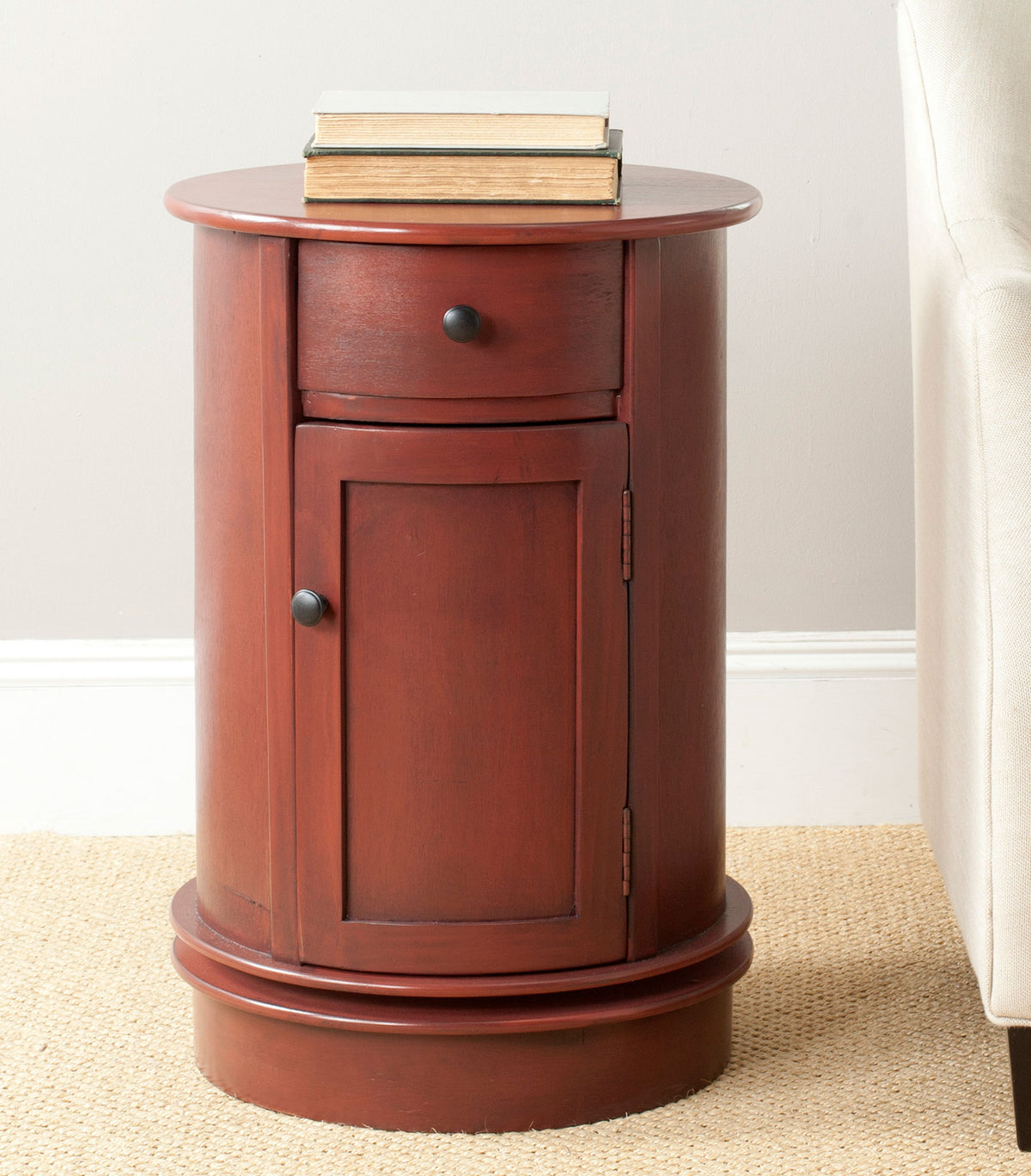 Rich red round table keeps books at hand beside a pale upholstered chair || AMH5712E || front_room