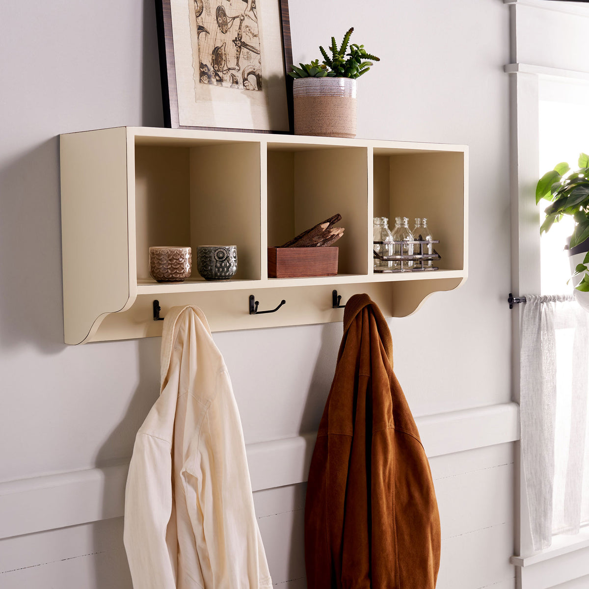 White wall cubbies display small accessories while hooks hold coats within easy reach