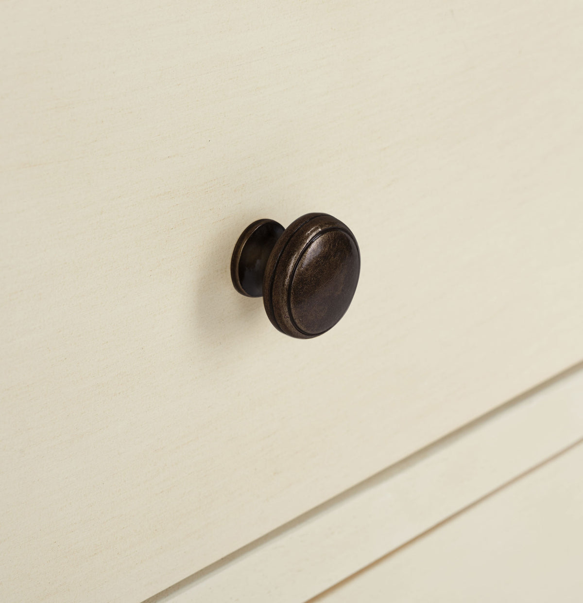 A dark bronze knob stands out against the creamy, softly distressed drawer front. || AMH6629D || handle_studio