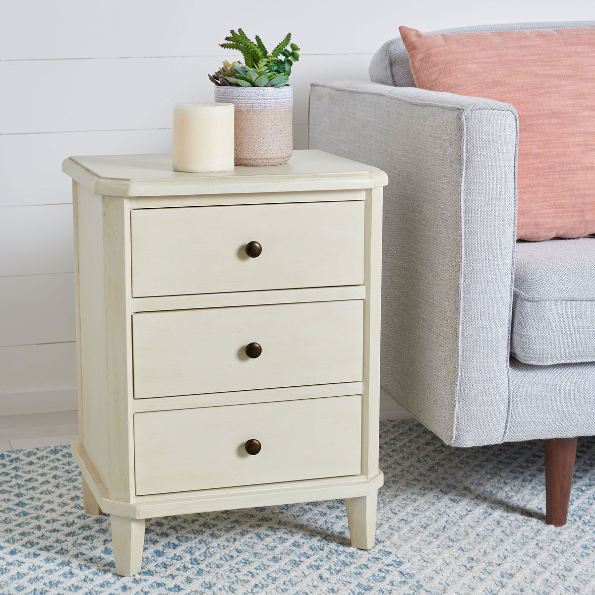 Three drawers in a creamy barley finish add useful storage beside a living room sofa. || AMH6629D || front_angle_room