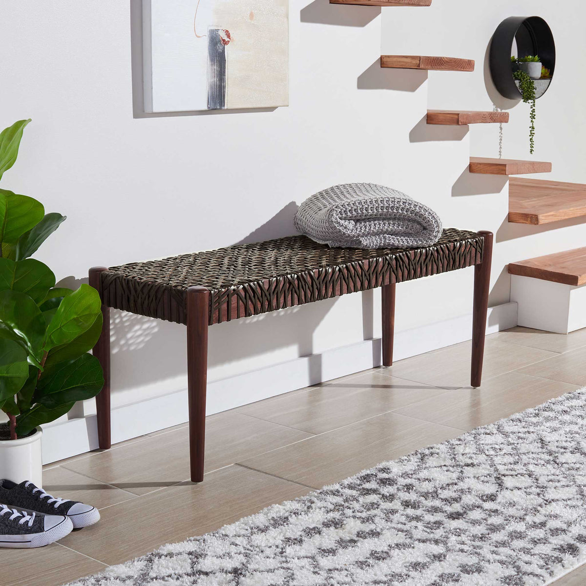 Brown leather weaving and tapered wood legs bring warm texture beside a staircase.