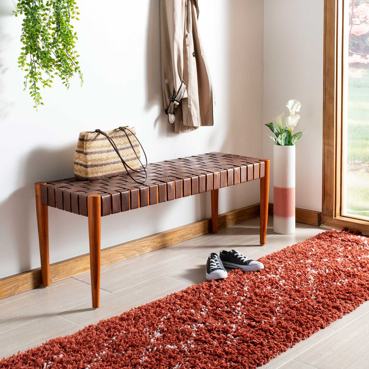 Woven cognac leather and warm wood bring natural texture to a slim entryway bench.