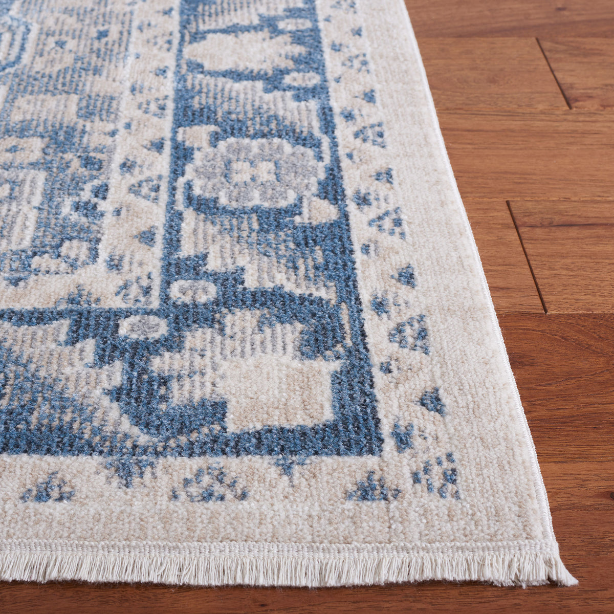 Fringed corner shows the intricate blue border and plush, low-profile pile on a beige ground || BLR208B-5 || corner_room