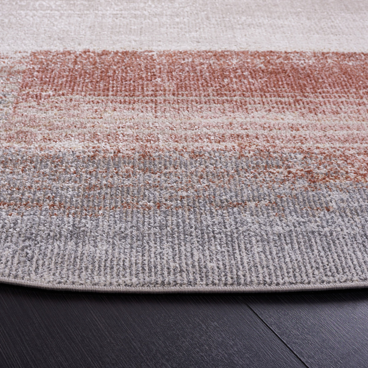 Soft, low-pile round rug with beige, rust, and blue patterning and a neatly finished edge || BLR216B-7R || detail_studio