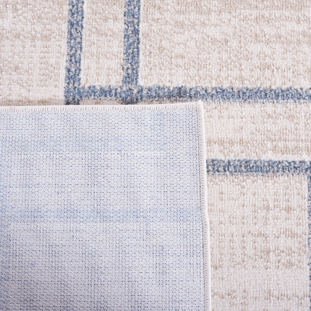 Corner flipped to showcase textured backing and stitched edge of beige and gray rug || BLR238B-5 || backing_studio