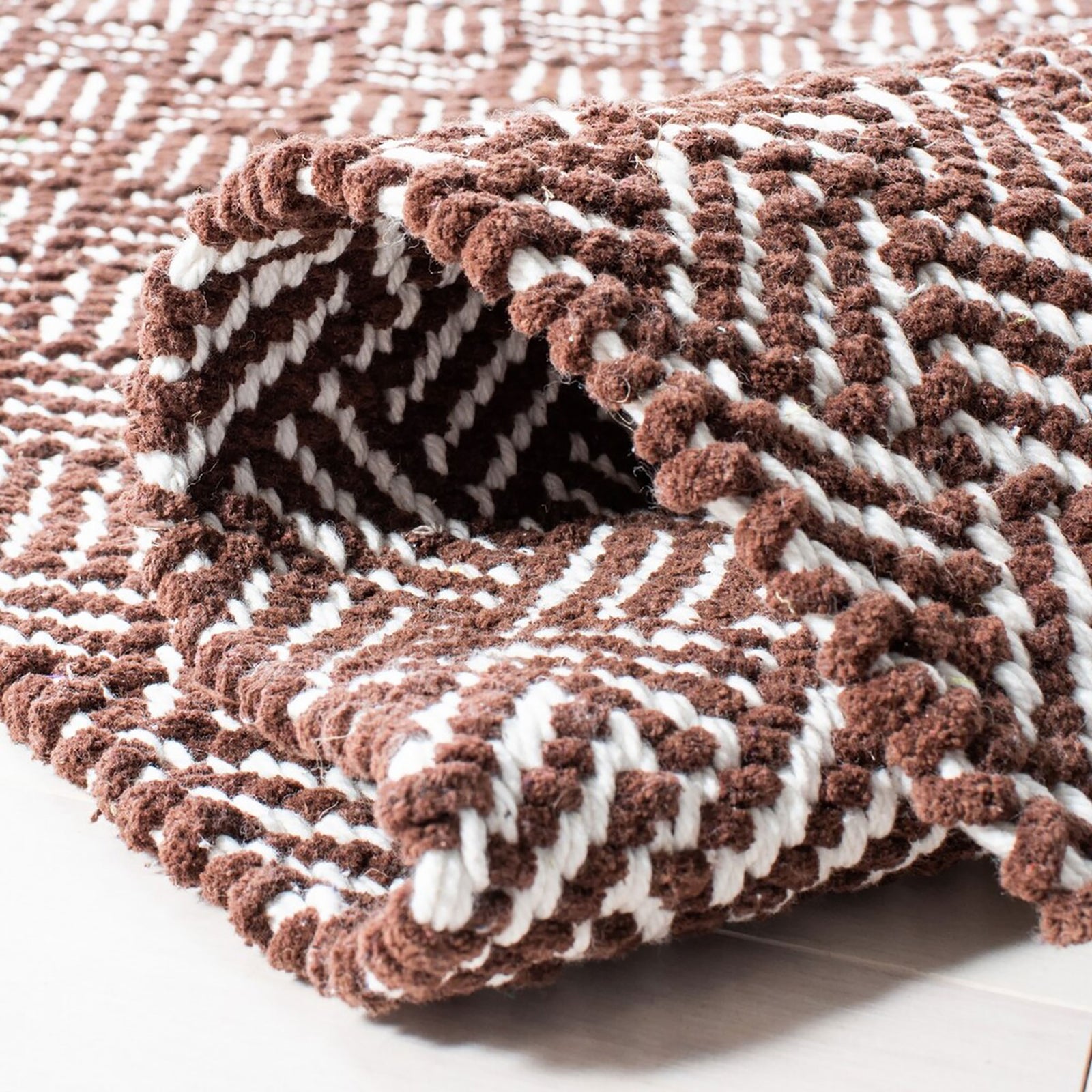 Folded brown and ivory herringbone rug showing its woven texture and flexible edges || BOS680A-5 || fold_room