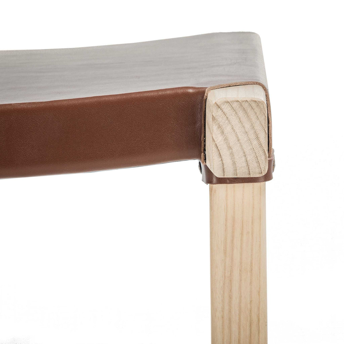A rich cognac leather seat wraps neatly around a light wood corner with visible fastening
