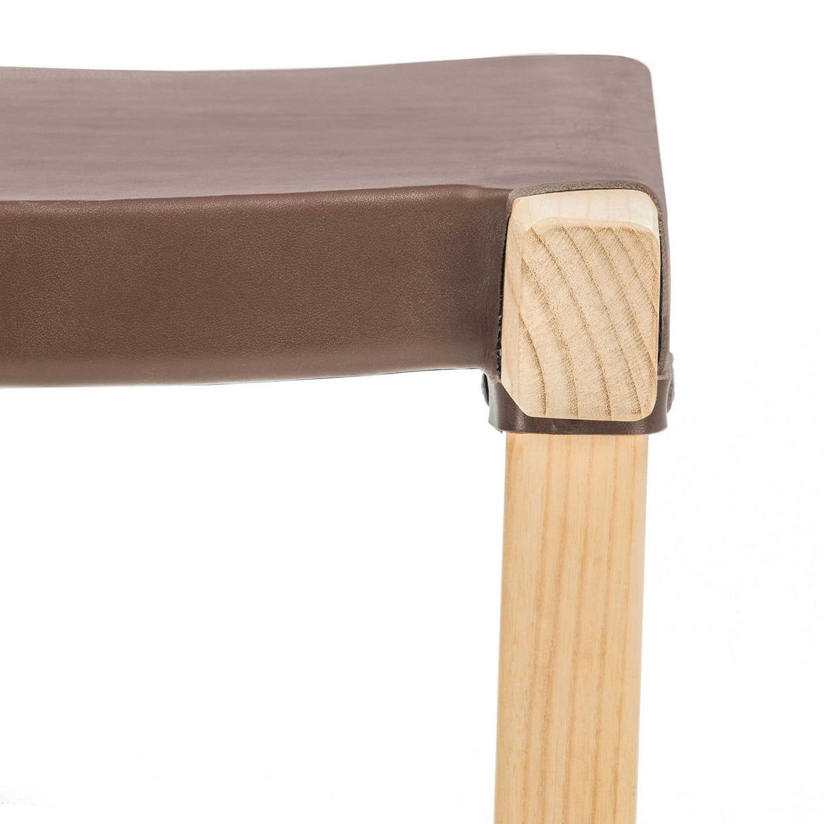 Cognac leather neatly meets a pale wood seat corner, revealing its carefully finished joint