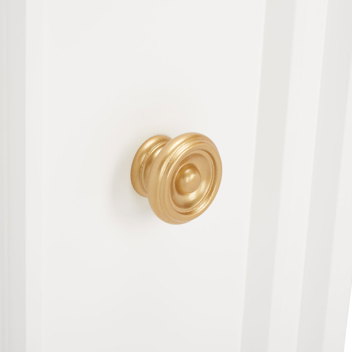 An ornate gold-tone knob adds a warm metallic accent to the crisp white cabinet door. || CHS5003A || handle_studio