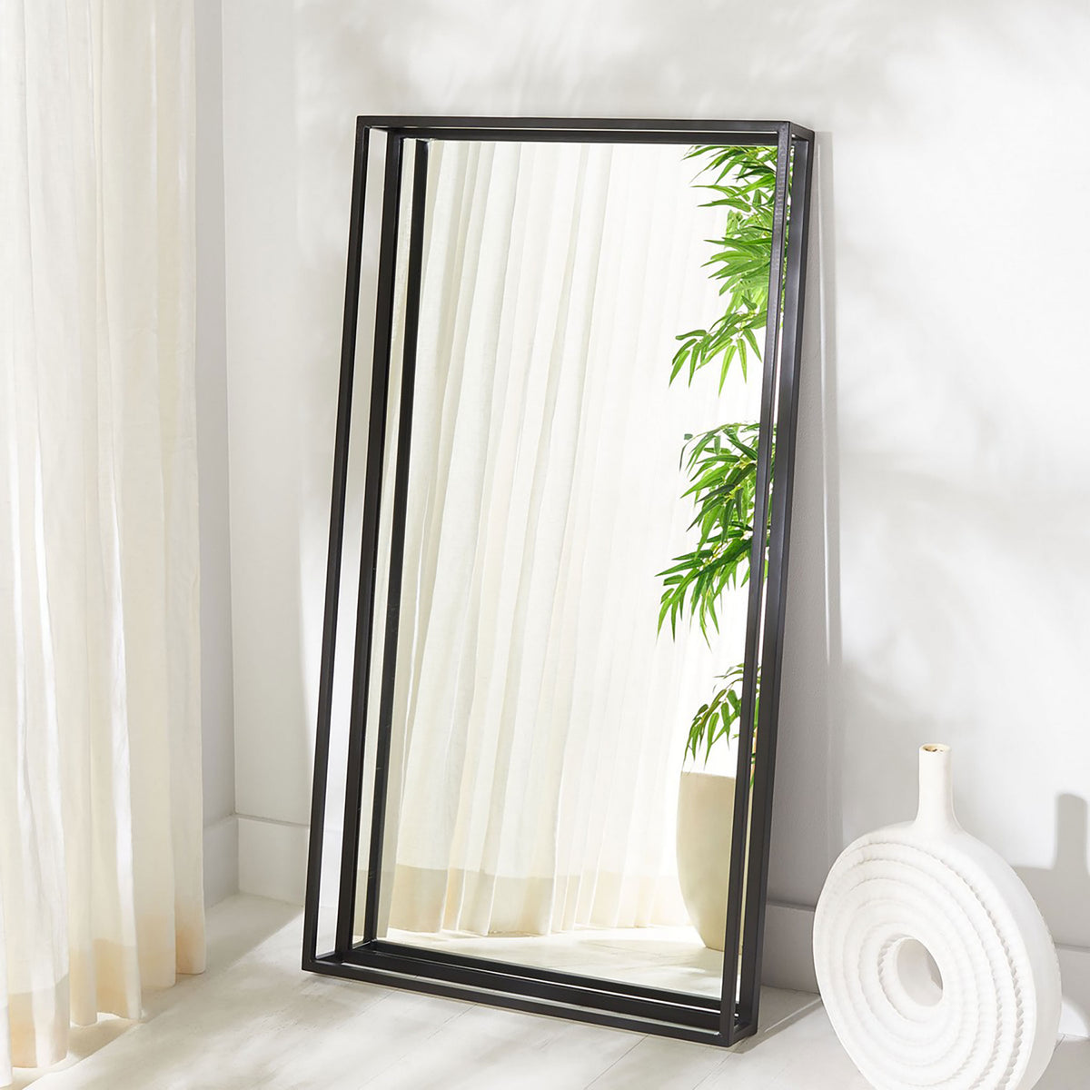 A tall black shadow box mirror adds depth and reflection to a bright room. || CMI1001A || front_angle_room