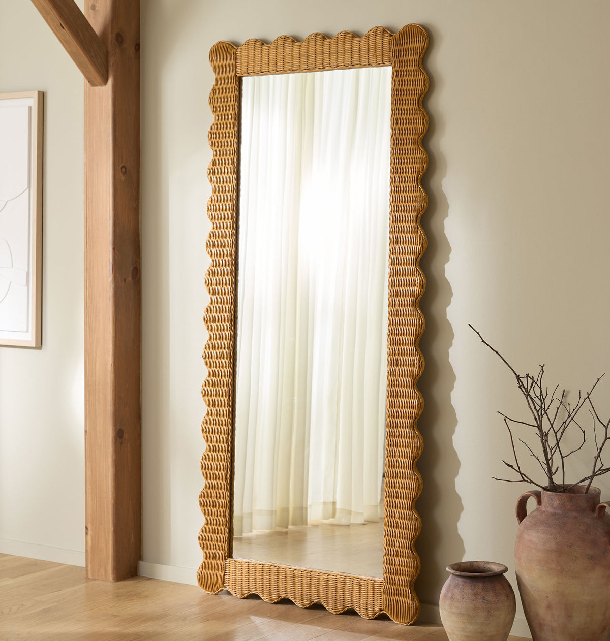 A tall rattan mirror with wavy edges brings warmth and texture to a neutral room. || CWK3021A || front_room