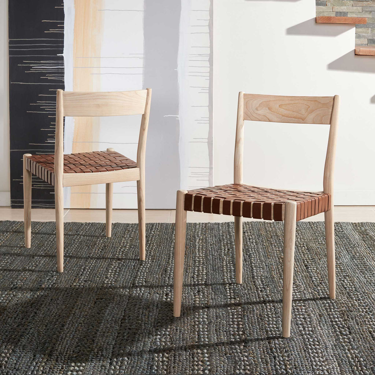 Two pale wood dining chairs bring woven cognac leather and open backs to an inviting interior