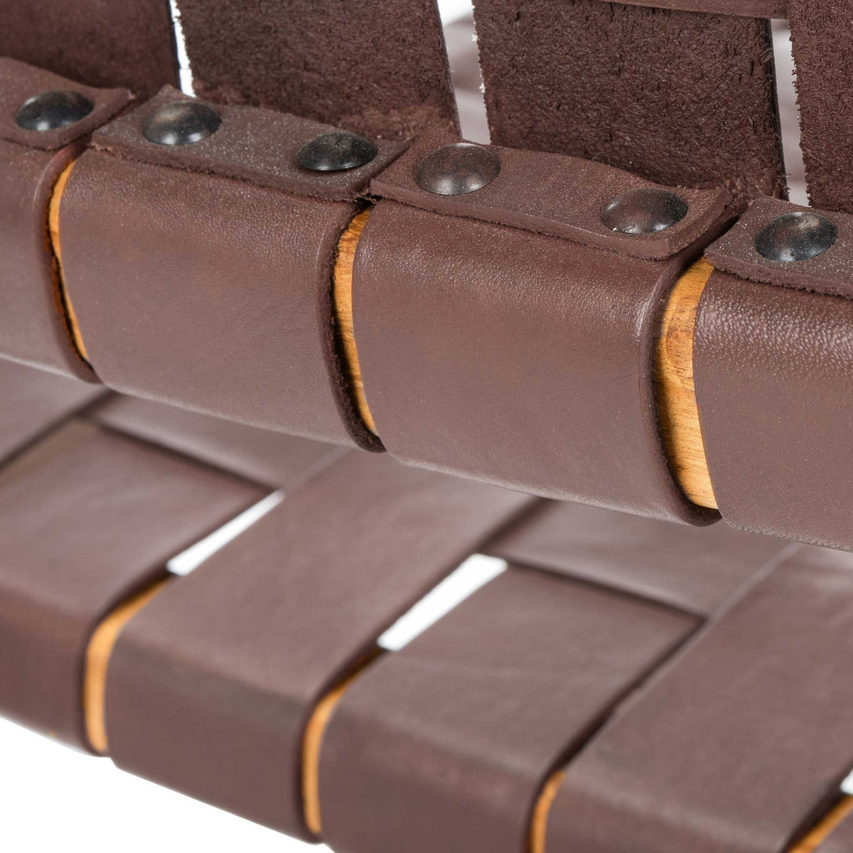 Dark rivets secure folded cognac leather straps around a rounded wood rail