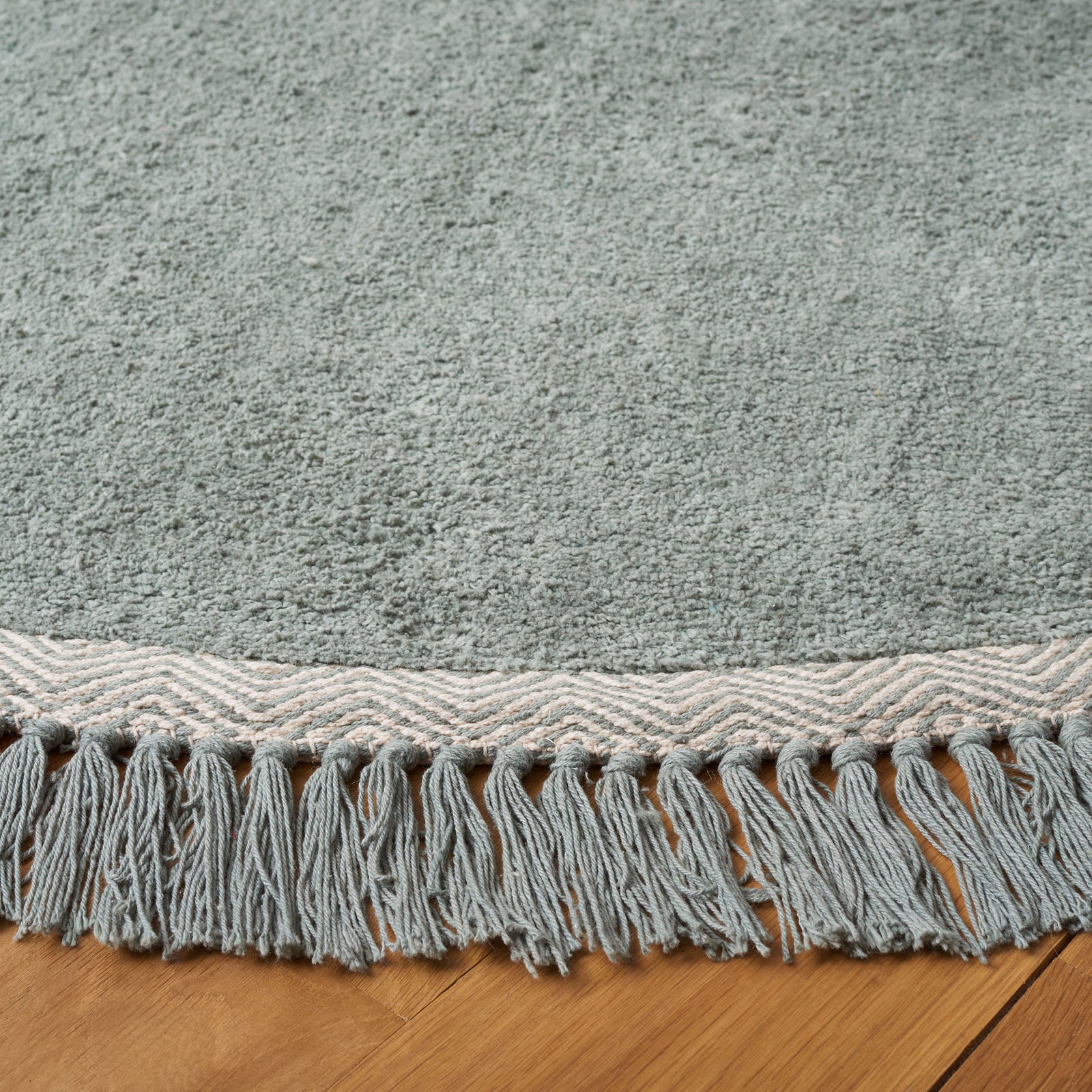 Ivory wave border and tasseled edge accent the soft teal pile || ECR202J-6R || detail_room