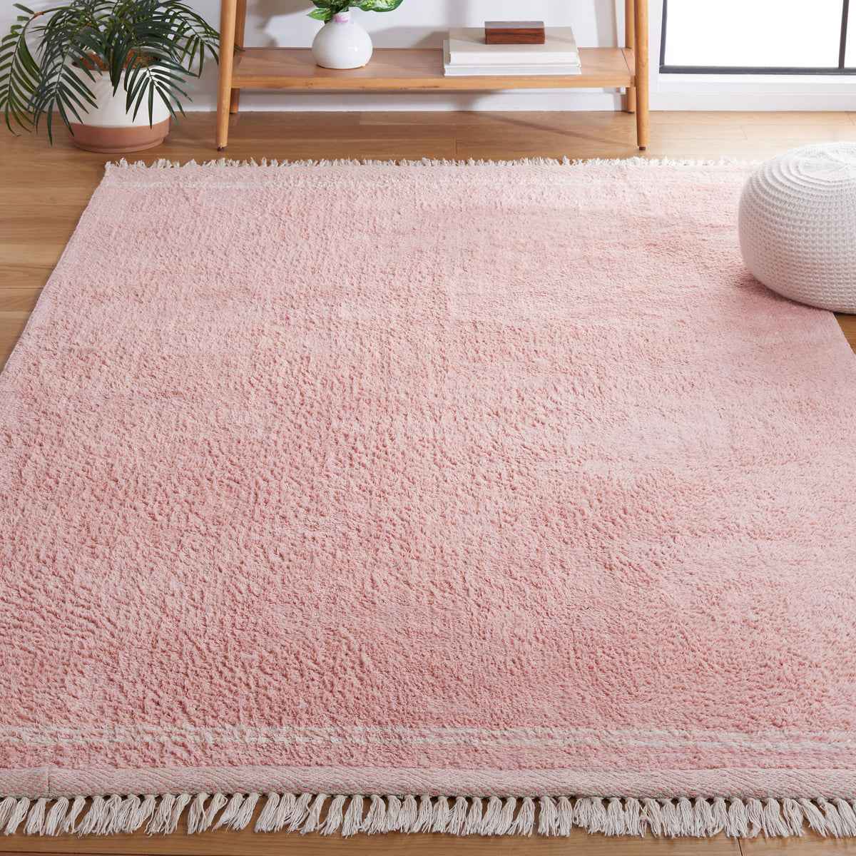 Soft pink rug brings warmth and texture to the living space, finished with ivory trim and tassels. || ECR211U-5 || top_angle_room