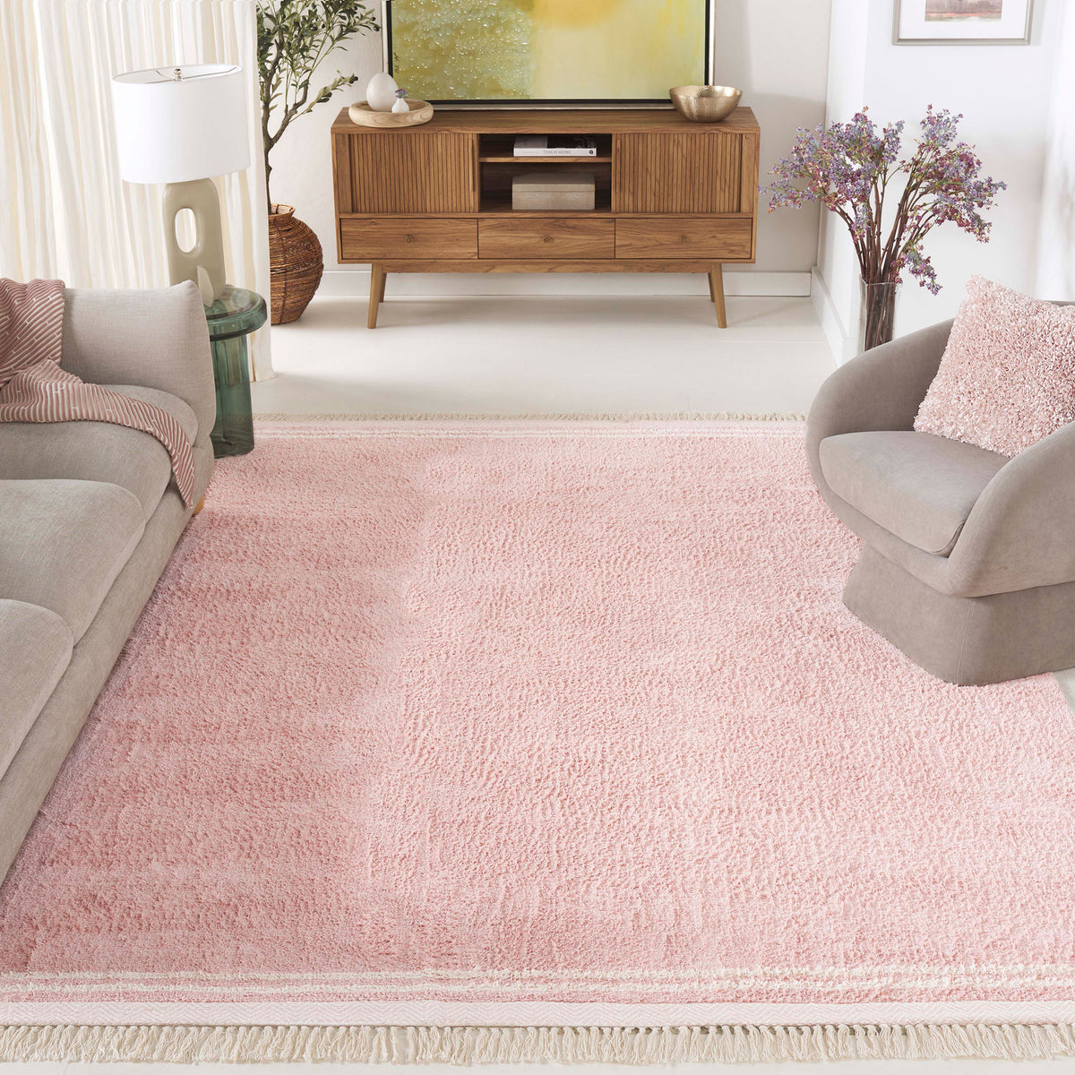 Warm pink area rug anchors the space with plush texture, ivory borders, and playful tassels. || ECR211U-8 || top_angle_room