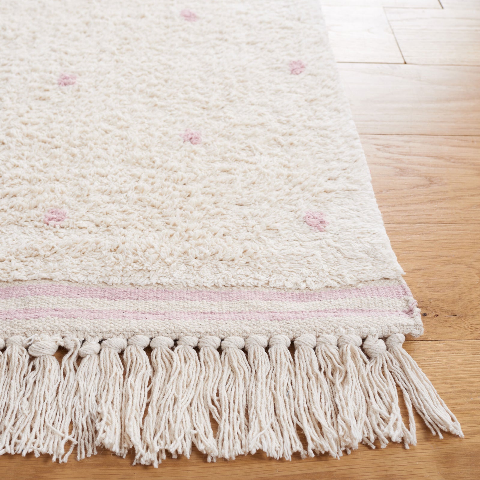 Textured ivory pile with pink dots and tasseled edge showing artisanal finish || ECR212U-5 || corner_room
