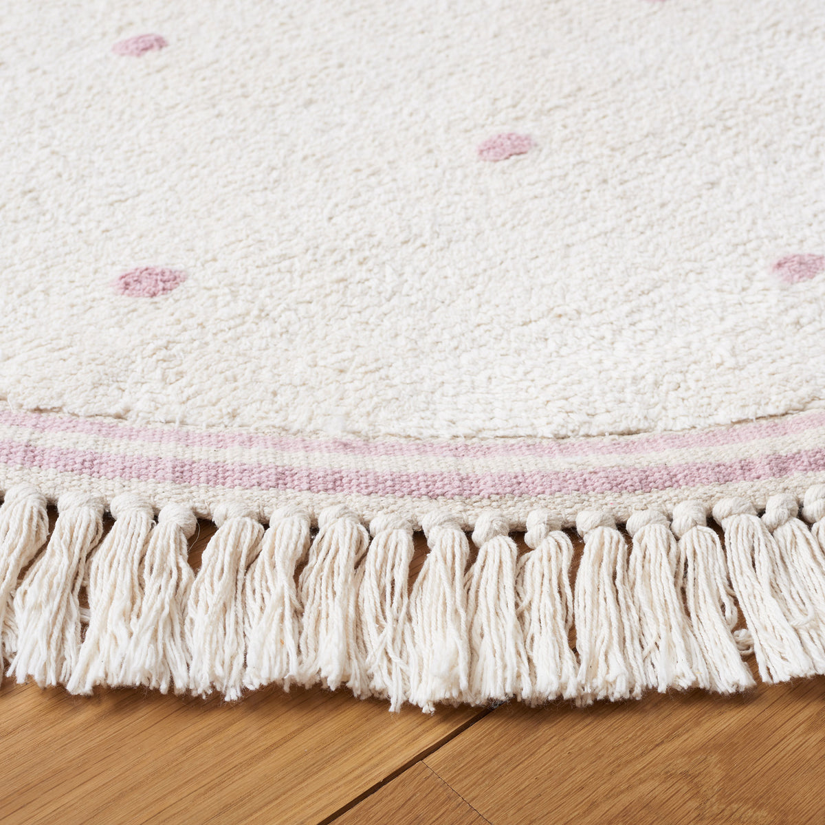 Tassel fringe and soft texture highlight the ivory round rug with soft pink dots. || ECR212U-6R || detail_room