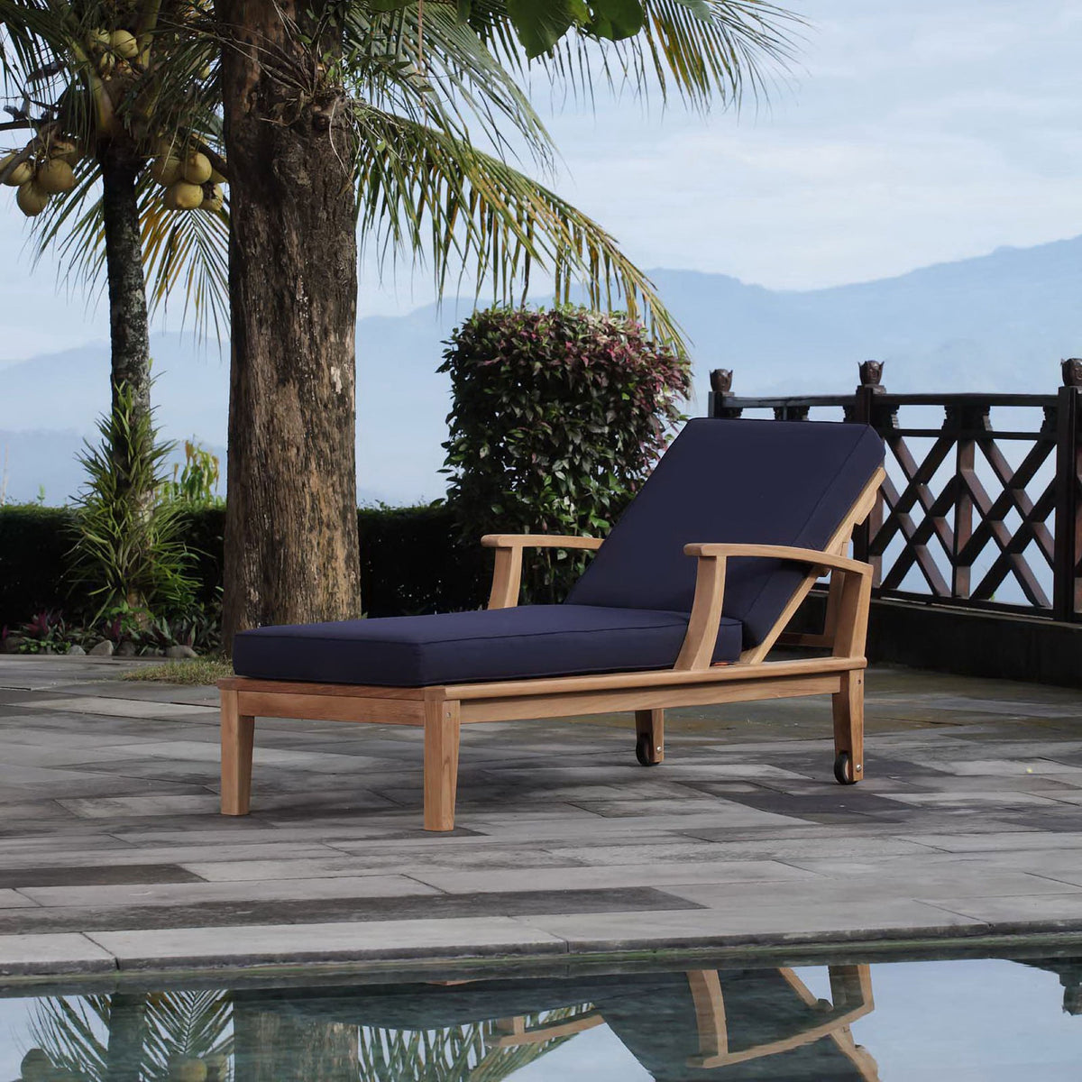 Teak chaise lounge with navy cushions styled by a poolside patio for relaxed outdoor lounging || EEI-1151-NAT-NAV-SET || front_angle_room