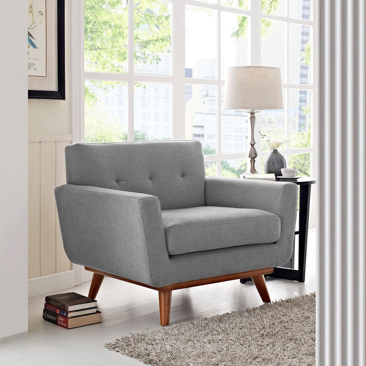 Soft gray fabric, button tufting, and warm wood legs make a cozy addition to a bright room.