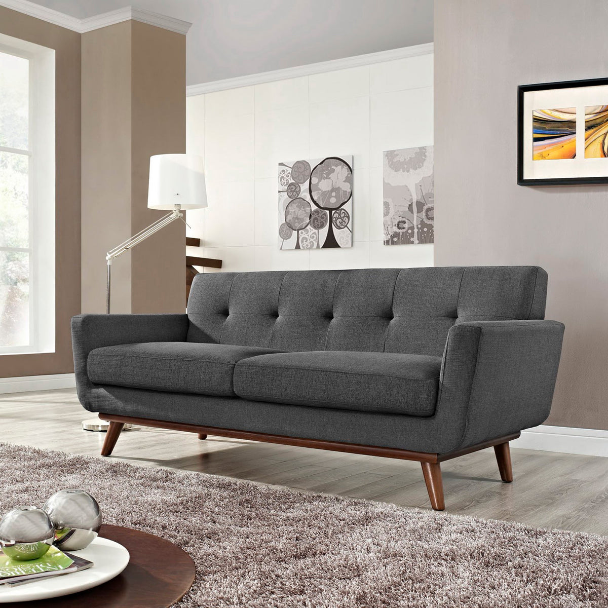 Charcoal gray cushions and subtle button tufting offer relaxed comfort with a warm wood finish