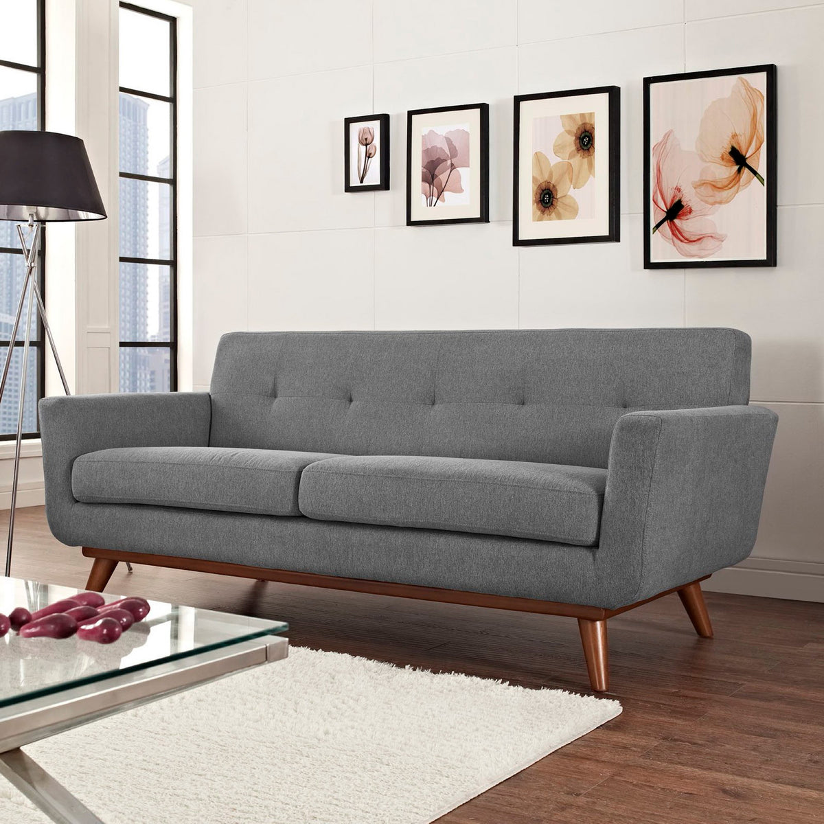 Gray fabric, a tufted back, and tapered wood legs create an inviting mid-century living room accent