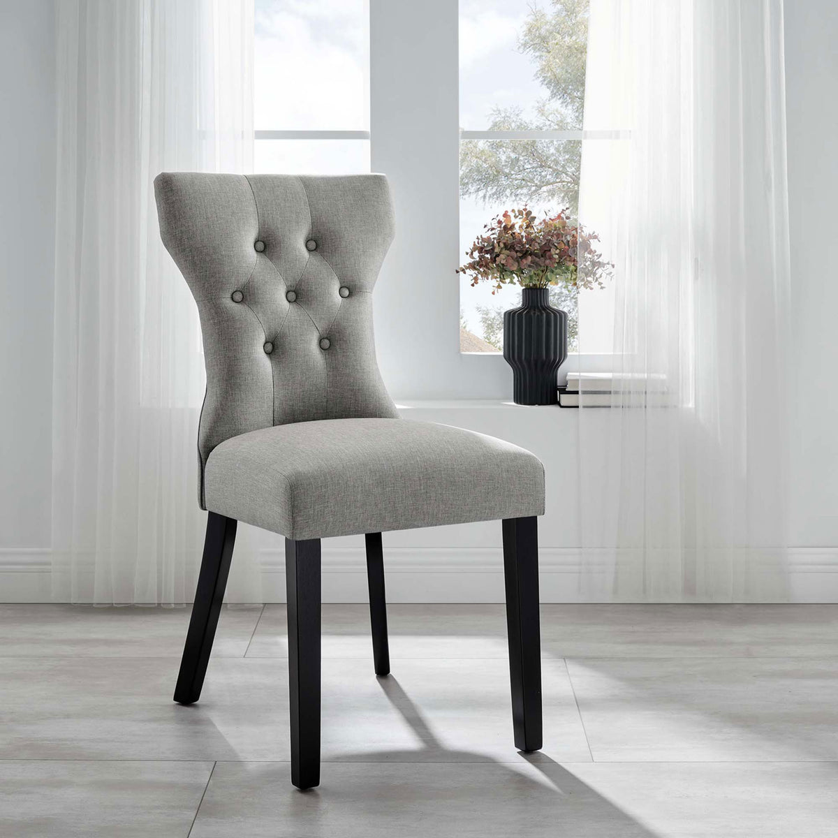 Light gray button-tufted dining chair styled in an airy room with large window and soft draped curtains || EEI-1380-LGR || front_angle_room