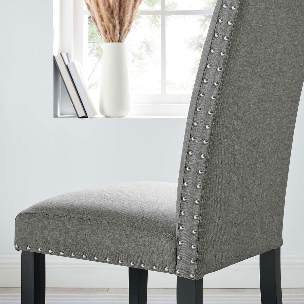 Light gray nailhead dining chair styled by a bright window with decorative vase and books. || EEI-1384-LGR || detail_room