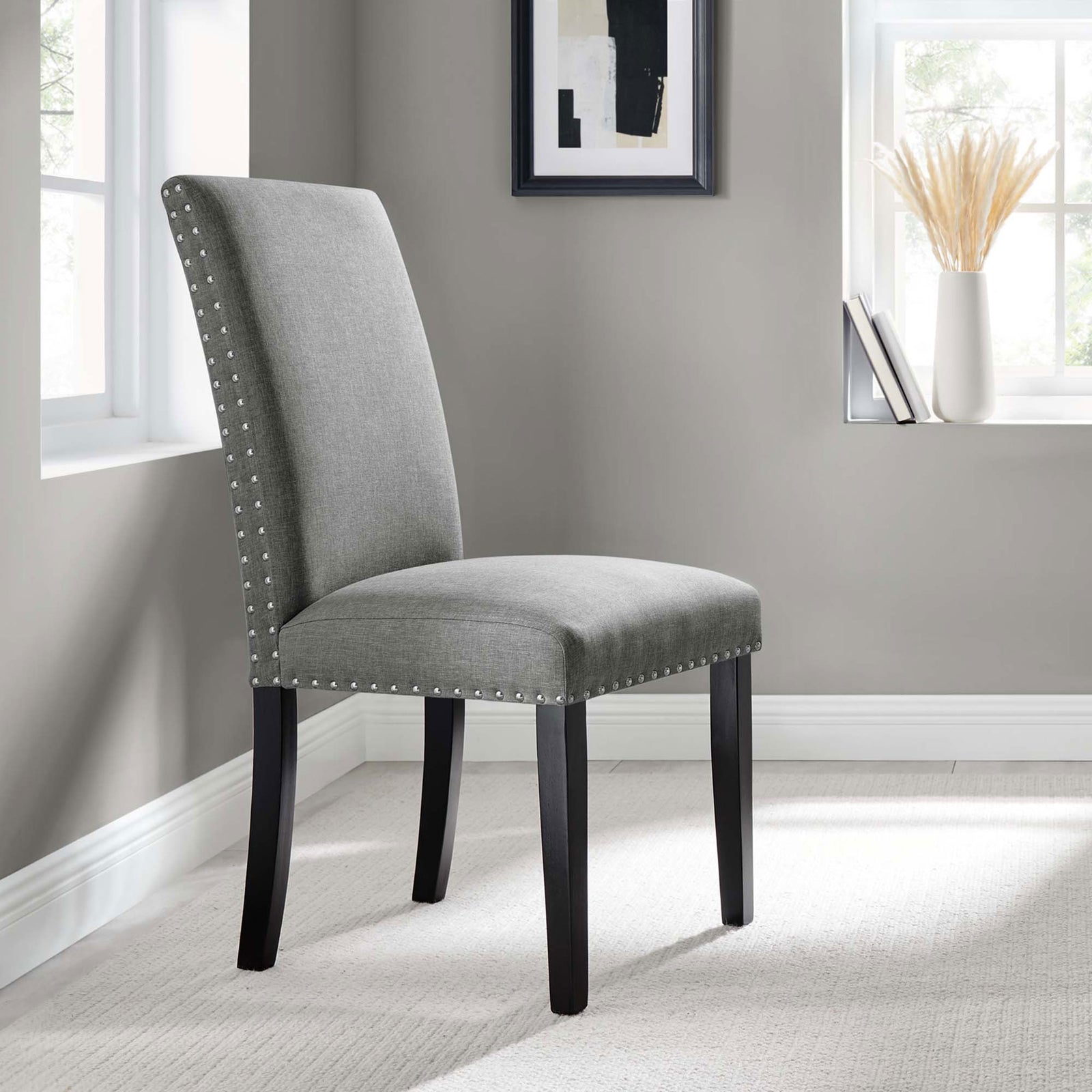 Parcel light gray upholstered dining chair with nailhead trim styled in a contemporary neutral dining nook. || EEI-1384-LGR || front_angle_room