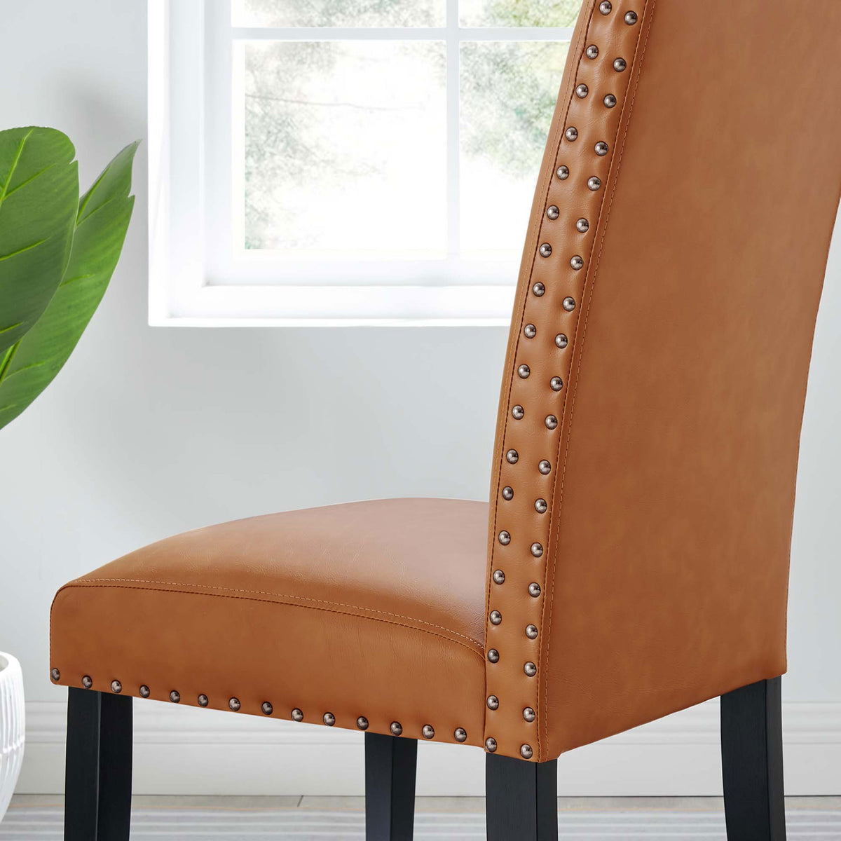 Close-up of tan faux leather dining chair seat and side detail in a sunlit room || EEI-1491-TAN || detail_room