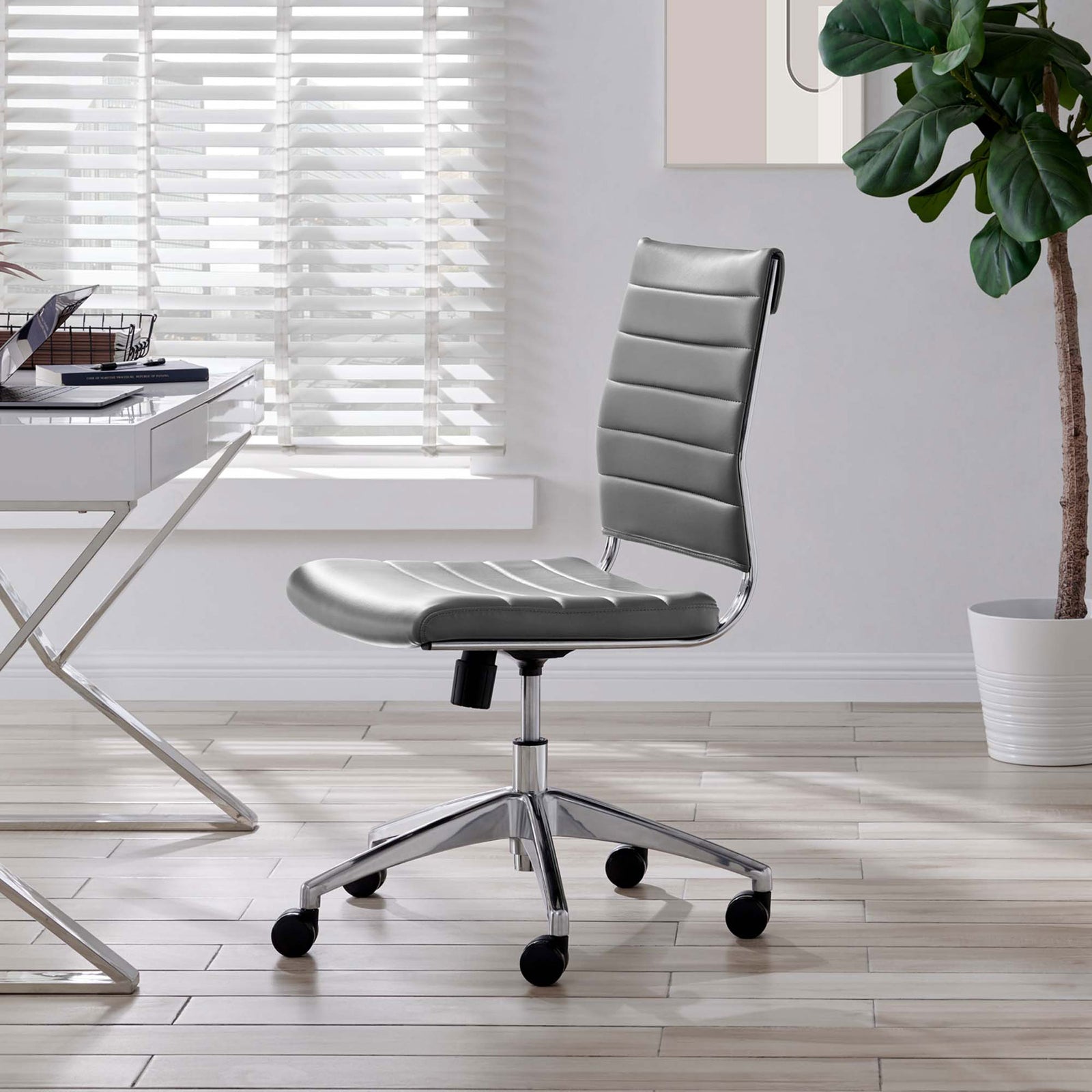 Gray armless office chair styled in a bright home workspace beside a modern glass desk and potted plant || EEI-1525-GRY || front_angle_room