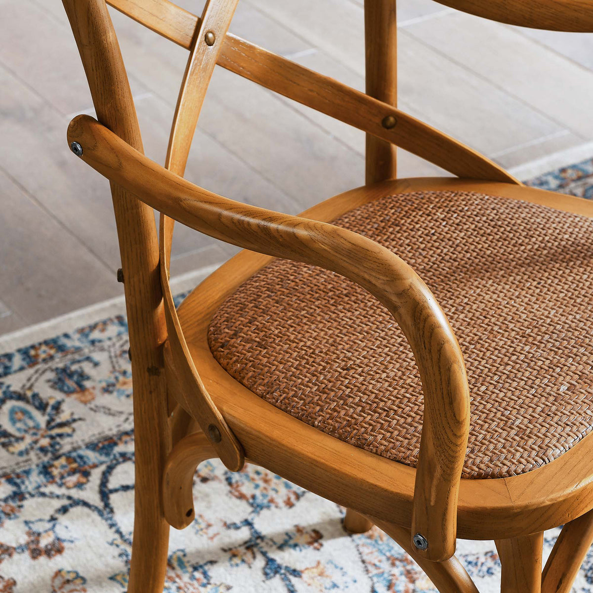 A richly woven rattan seat meets smoothly curved wood arms and warm walnut tones