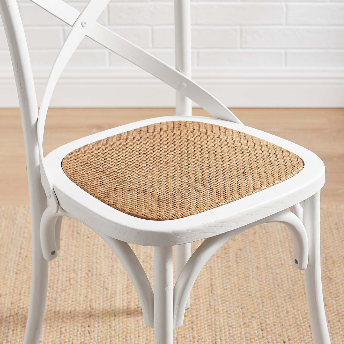 Pale rattan weave warms the crisp white seat frame above graceful arched supports
