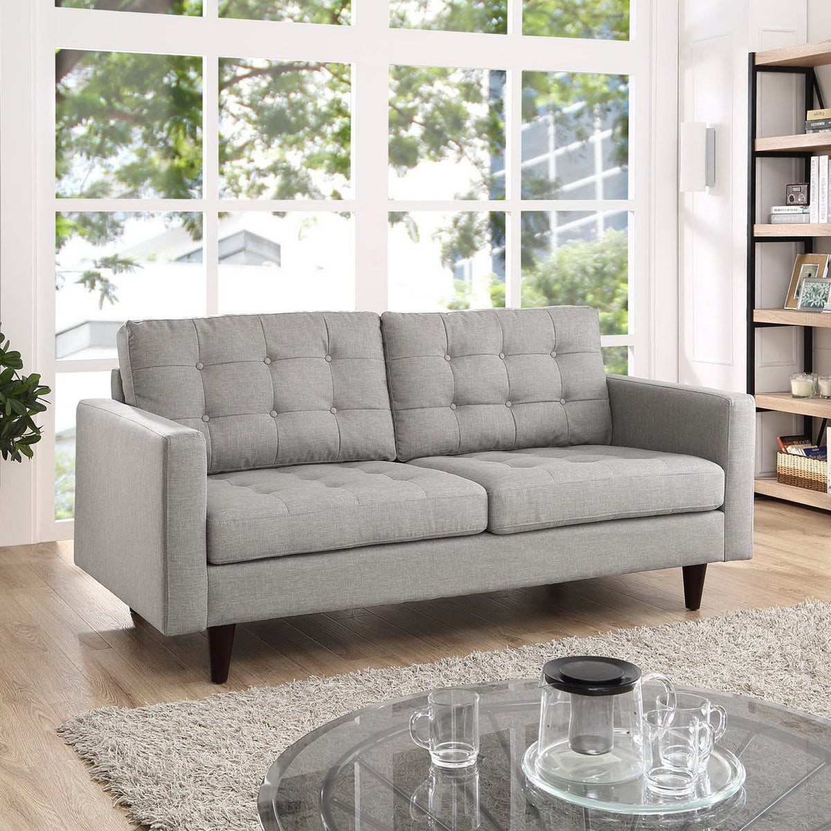 Light gray loveseat pairs plump button-tufted back cushions with inviting seats and dark wood legs.