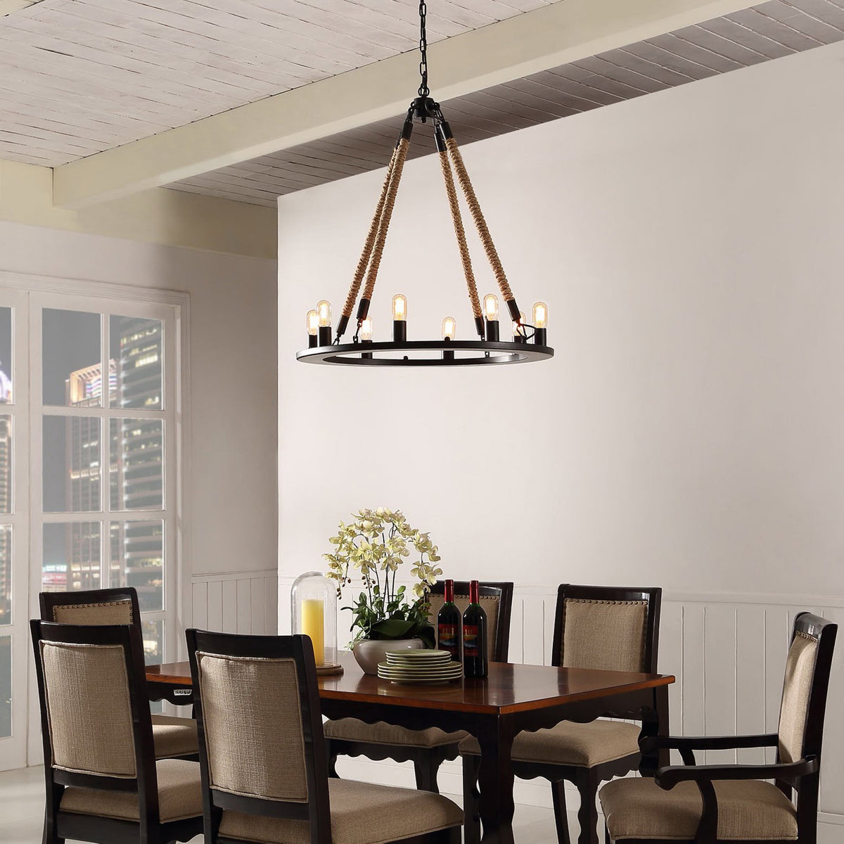 Glowing bulbs line a black steel chandelier suspended by rope above a dining table