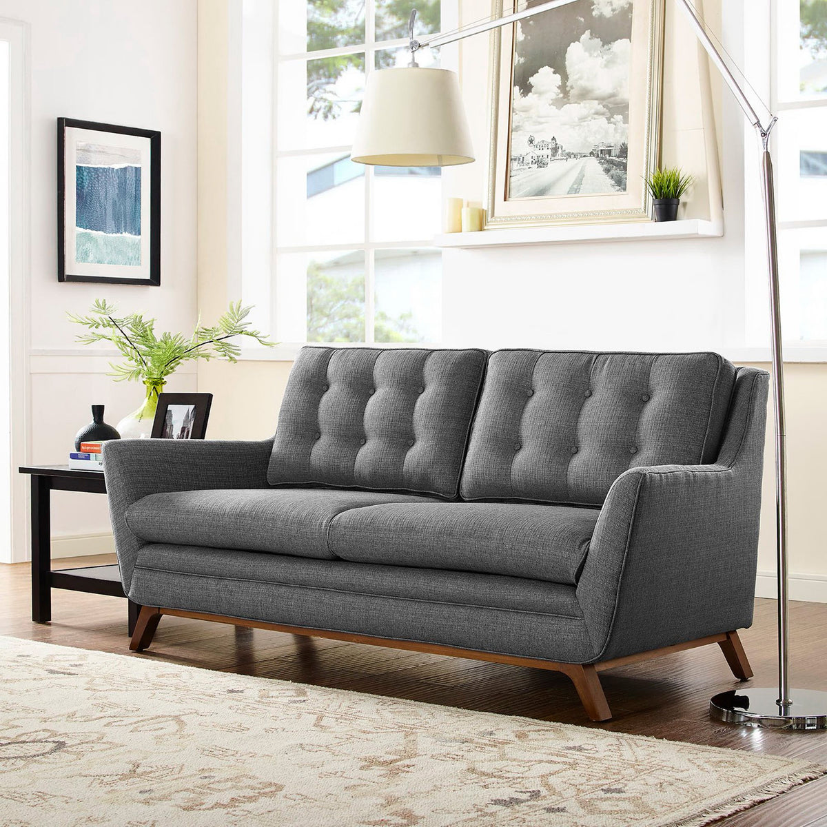 Tufted gray cushions, flared arms, and a warm wood base make this loveseat a cozy focal point
