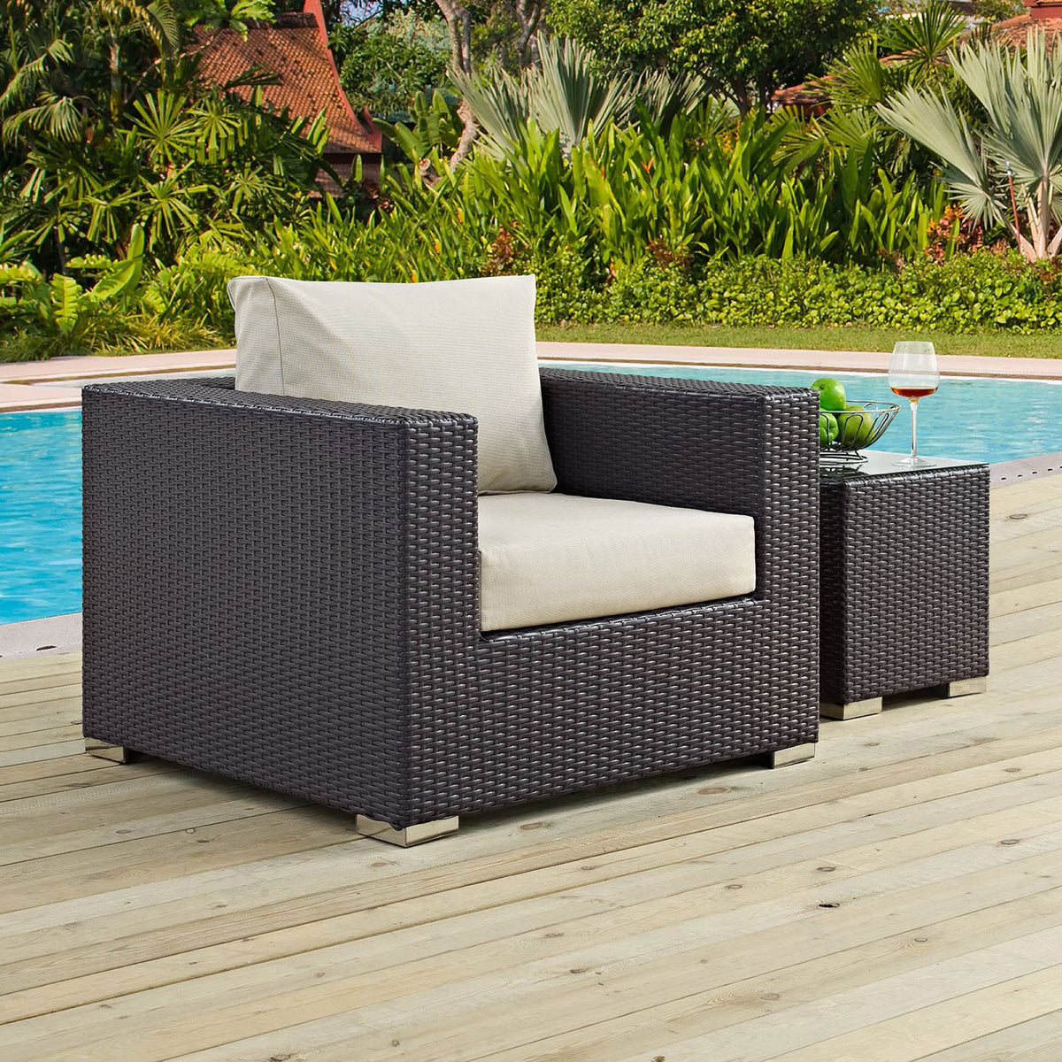 Espresso wicker armchair with beige cushions arranged on a poolside deck with matching side table || EEI-1906-EXP-BEI || front_angle_room