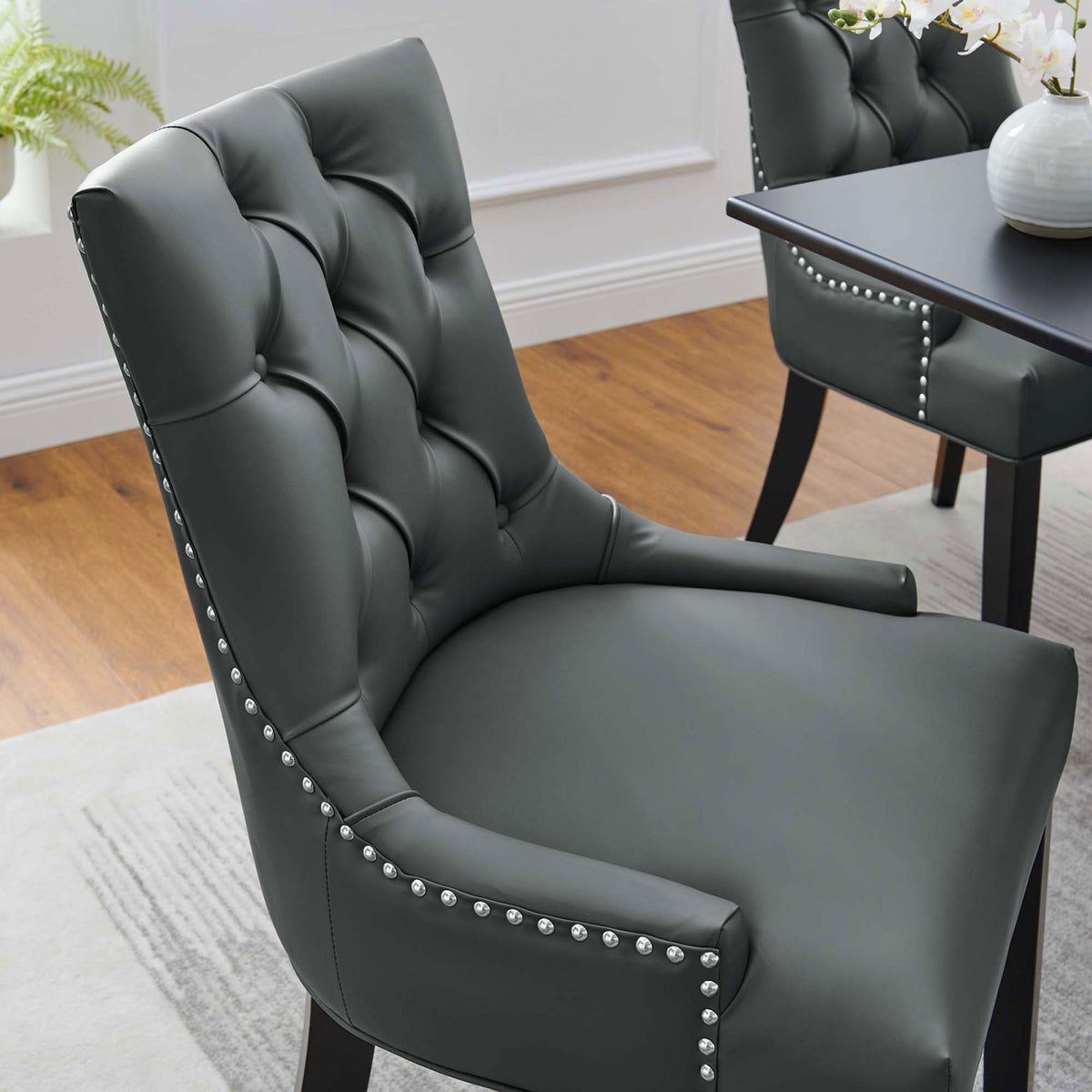 Gray tufted vegan leather dining chair drawn up to a dining table showing plush seat and nailhead-trimmed sides || EEI-2222-GRY || detail_room