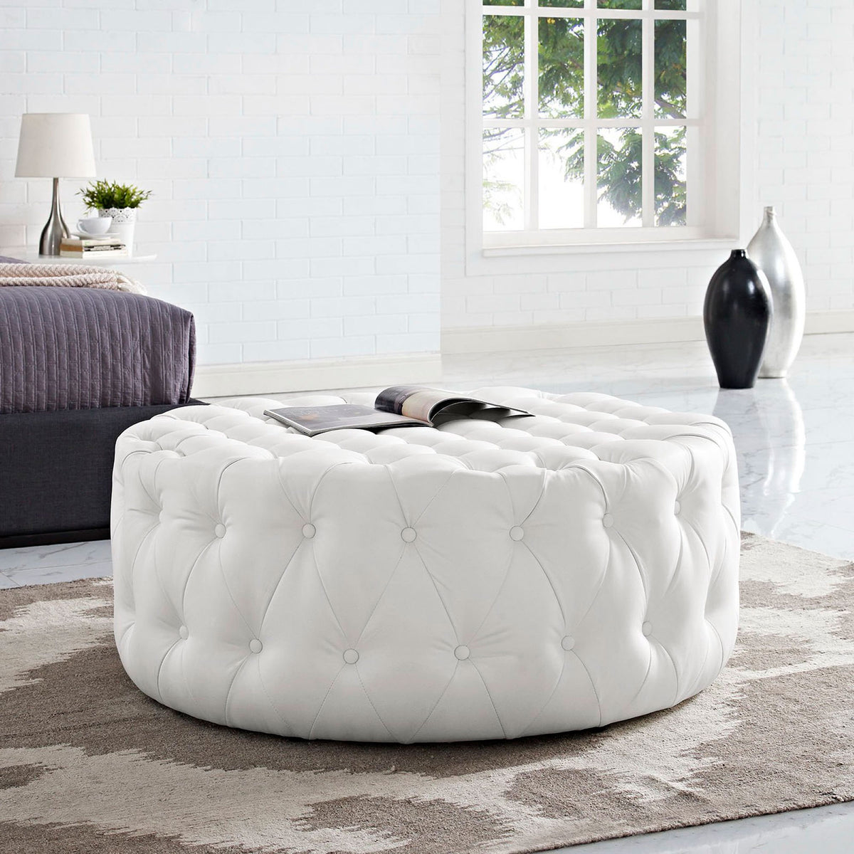 White tufted round ottoman styled in a modern bedroom as a chic centerpiece on a rug || EEI-2224-WHI || front_angle_room