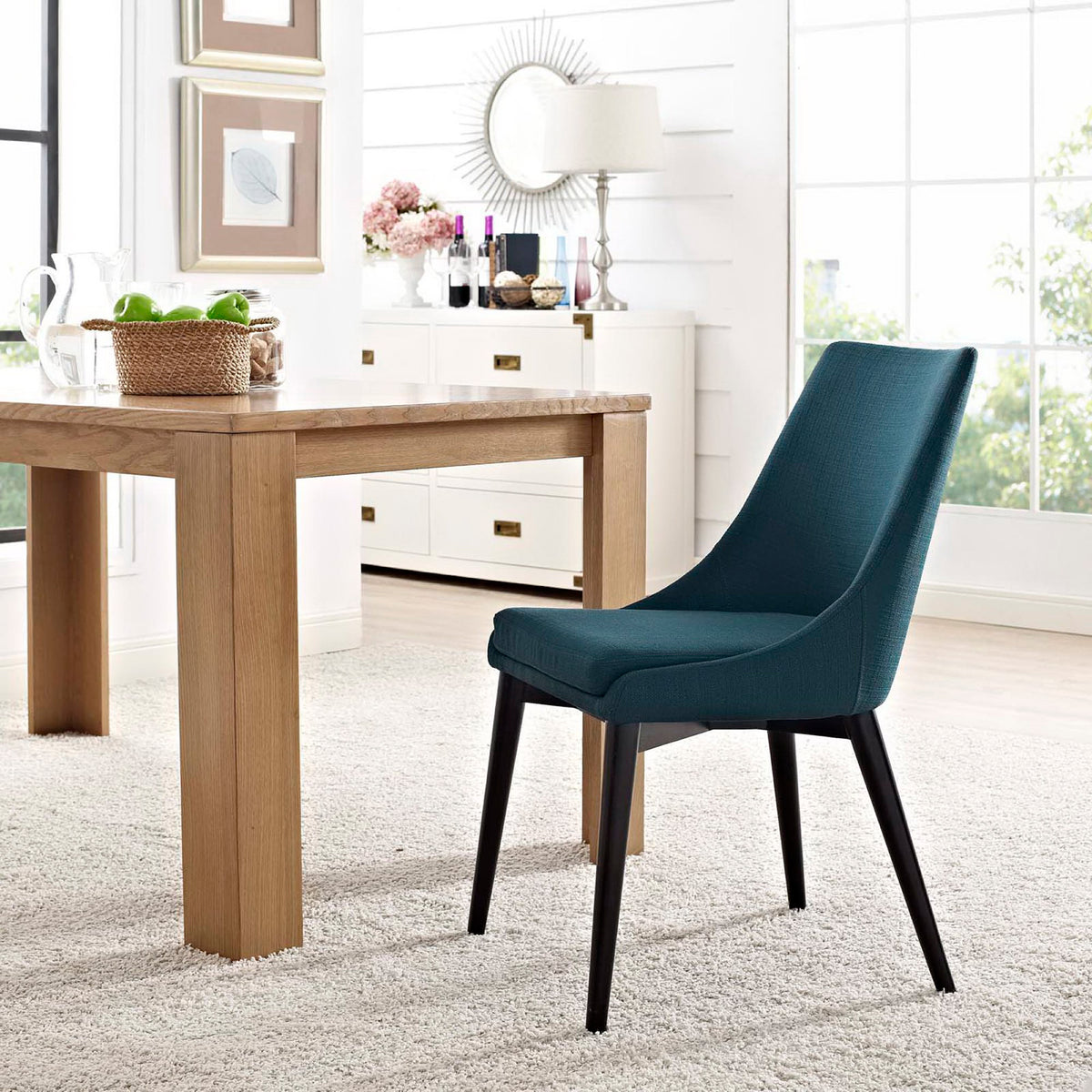 A vivid azure chair brings soft seating and sleek black legs to a bright dining space.