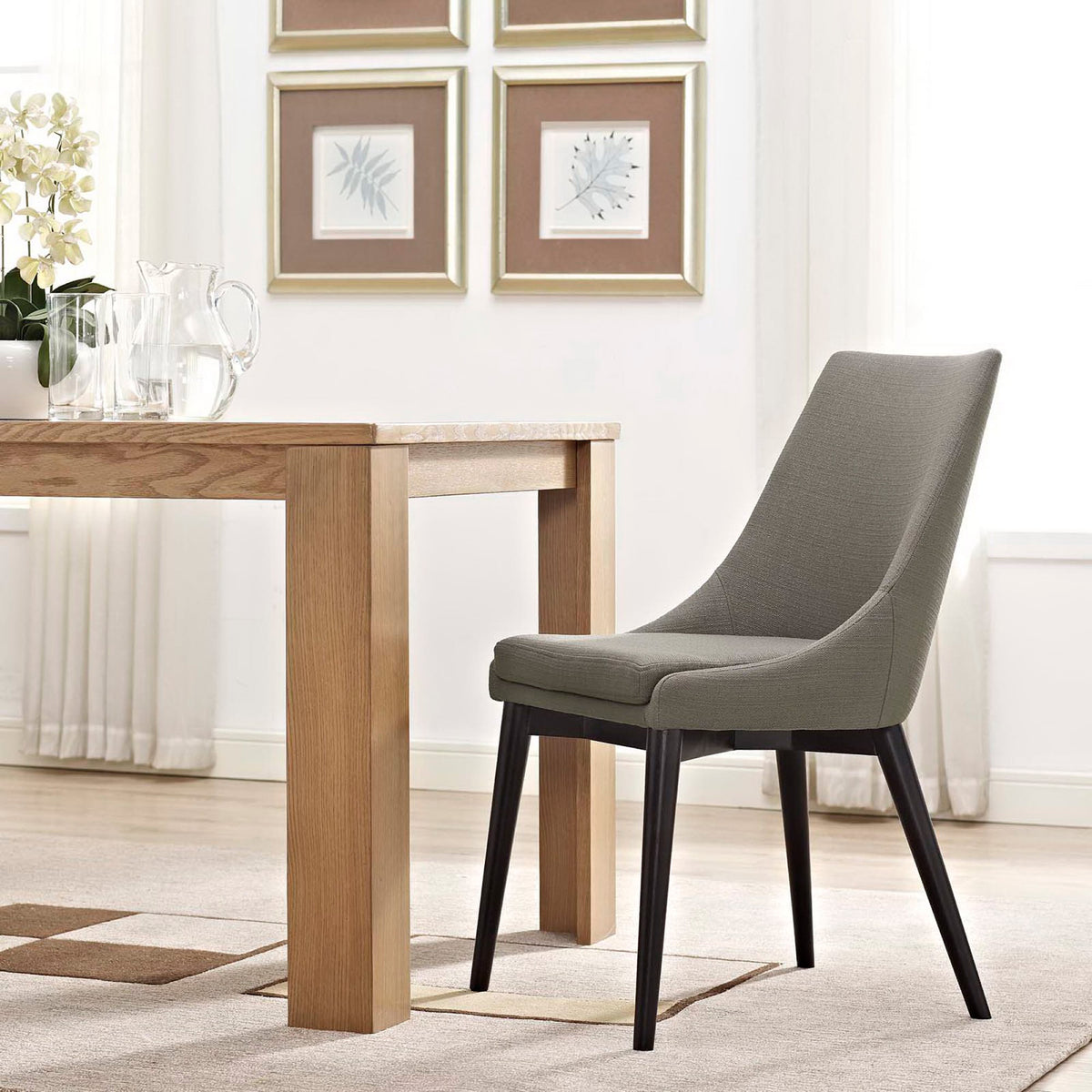 A granite gray cushioned chair with slender dark legs suits a bright, airy dining area.