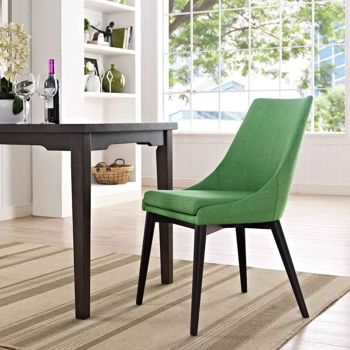 A bright green chair with a cushioned seat and slim black legs adds energy to the dining room.