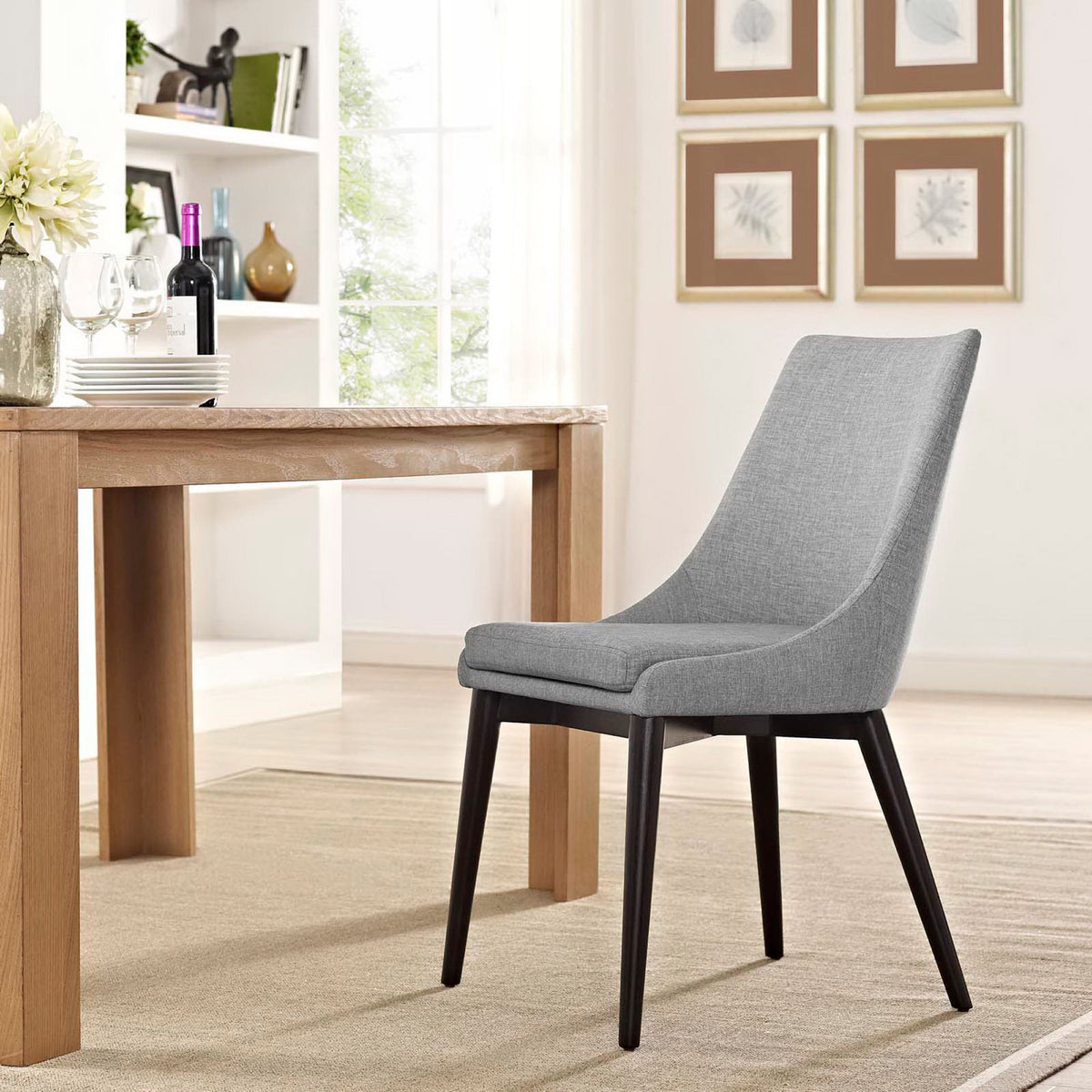 A light gray dining chair blends a plush seat and graceful curves with sleek dark legs.
